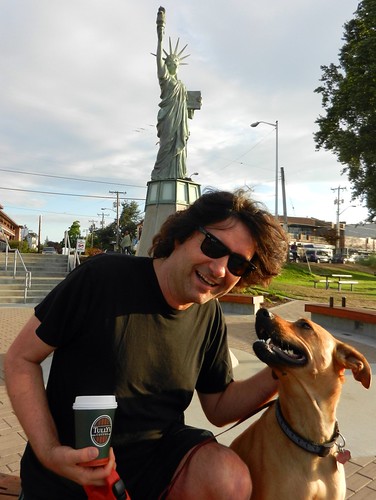 Behind sunglasses, Nick Boseck with a cuppa Tully's joe, Rosie the dog, under the Statue of Liberty at Alki Beach, West Seattle, Washington, USA by Wonderlane