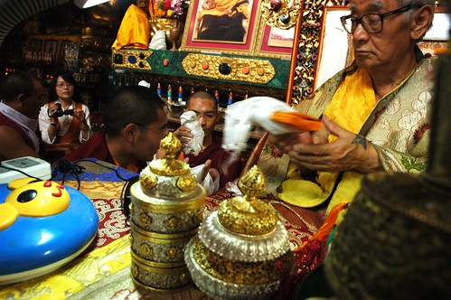 Videographer pauses during a mandala offering, His Holiness Jigdal Dagchen Sakya accepts a book, symbol of the Buddha's Dharma, monks, gold and silver high ranking lama's desk items, child's lamp base, Sakya Lamdre, Tharlam Monastery of Tibetan Buddhism,  by Wonderlane
