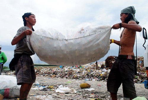 Two young scavengers carry a sackload of recyclables from the Inayawan landfill. 
