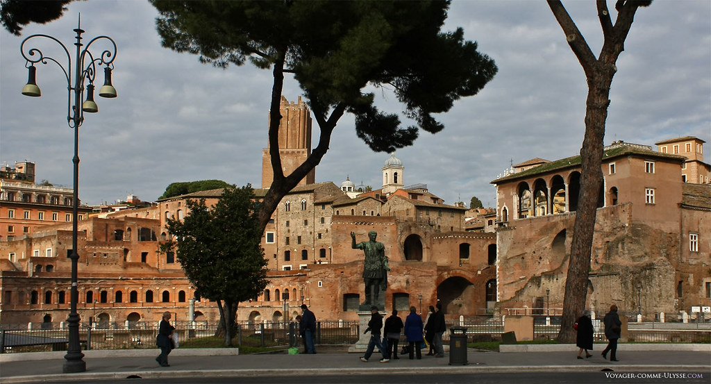 A via dei Fori Imperiali está decorada com estátuas dos grandes dirigentes romanos, como aqui, a estátua de Trajano, de frente para os mercados de Trajano.