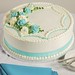 This beautiful and versatile cake is accented with aqua and white flowers, green leaves and aqua ribbon. 