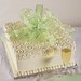 This whimsical gift box with icing lid is packed with flavor for you and your guests. Shown in white buttercream with a green and silver ribbon.