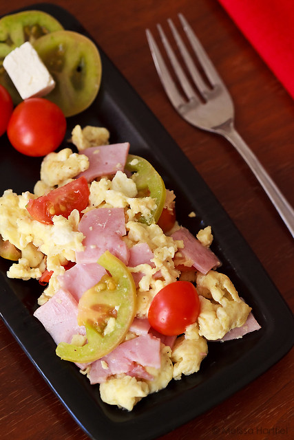 Scrambled eggs with green and red tomatoes, feta and ham