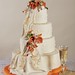 Elegant offset tiers are wrapped with smooth as silk fondant.  A cascading fondant drape is anchored by a bouquet of calla lilies on the second tier and crowned by a blossom of calla lilies on the top.  Handpainted decorations on the fondant drape and a dramatic color scheme complete this elegant cake.